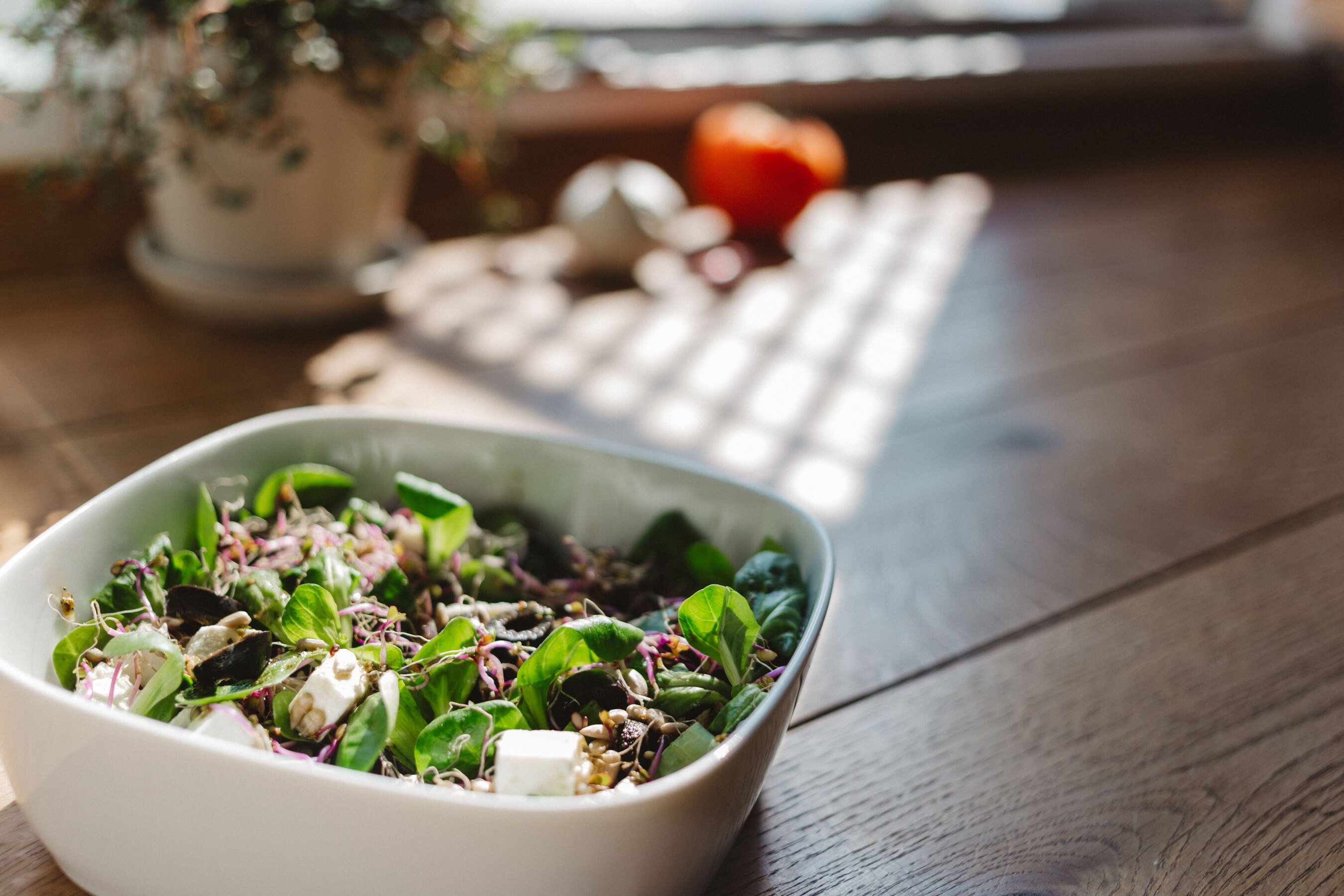 A bowl of leafy salad on a sunlit table